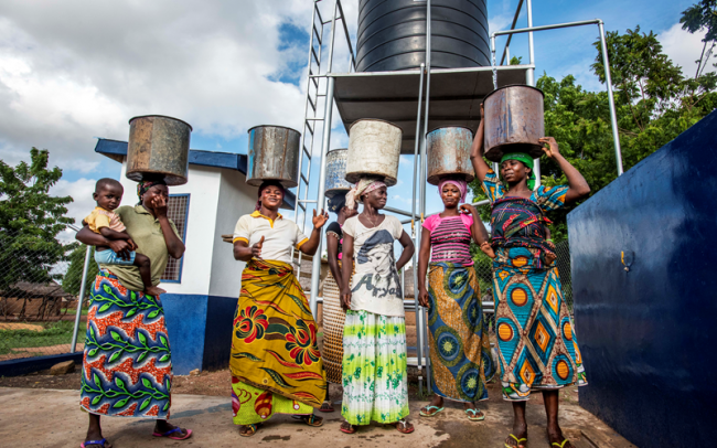Africa women with water buckets on their heads. Photo: Raymond Rutting/Simavi