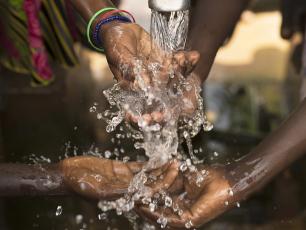   Stream of water pouring into children’s hands in southern Burkina Faso. Photo: Jadwiga Figula / Getty Images. Stream of water 