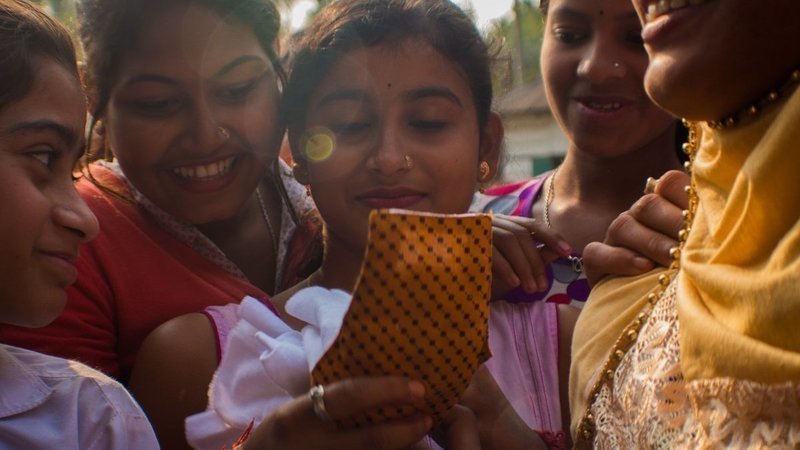 Assam, India - groups of girls looking at sanitary napkin